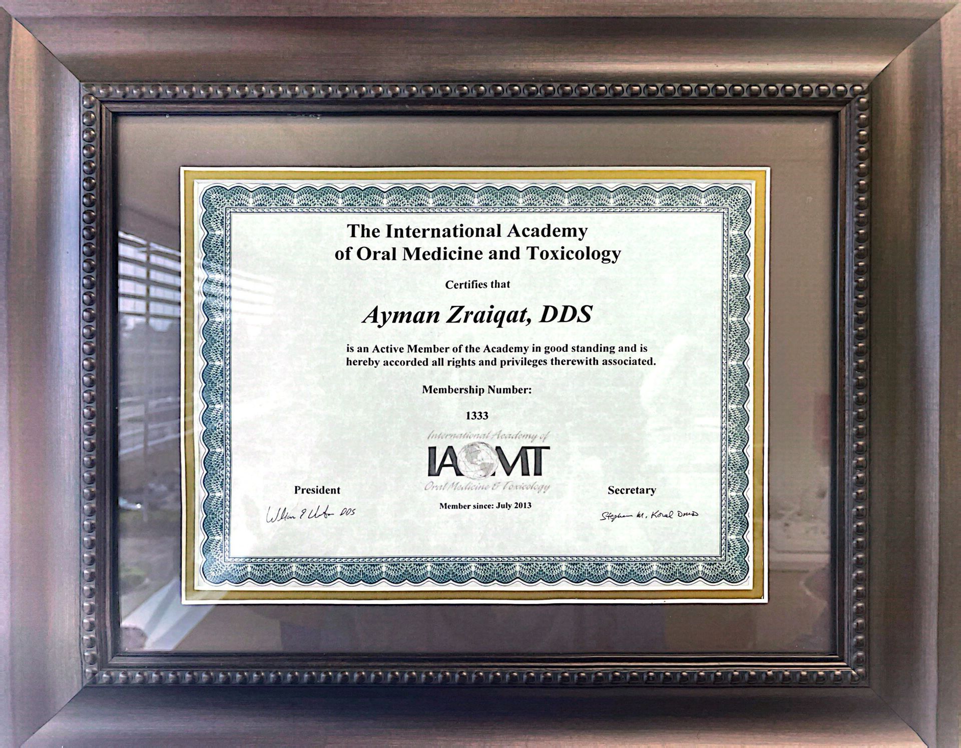 A framed certificate from the International Academy of Oral Medicine and Toxicology, certifying Ayman Zraiqat, DDS, as an active member.